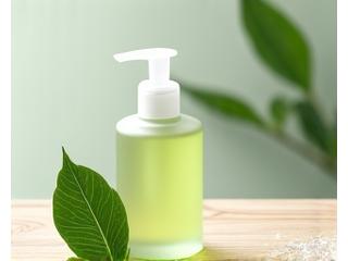 Botol pembersih muka lembut dengan daun hijau dan titisan air, menunjukkan kesegaran.